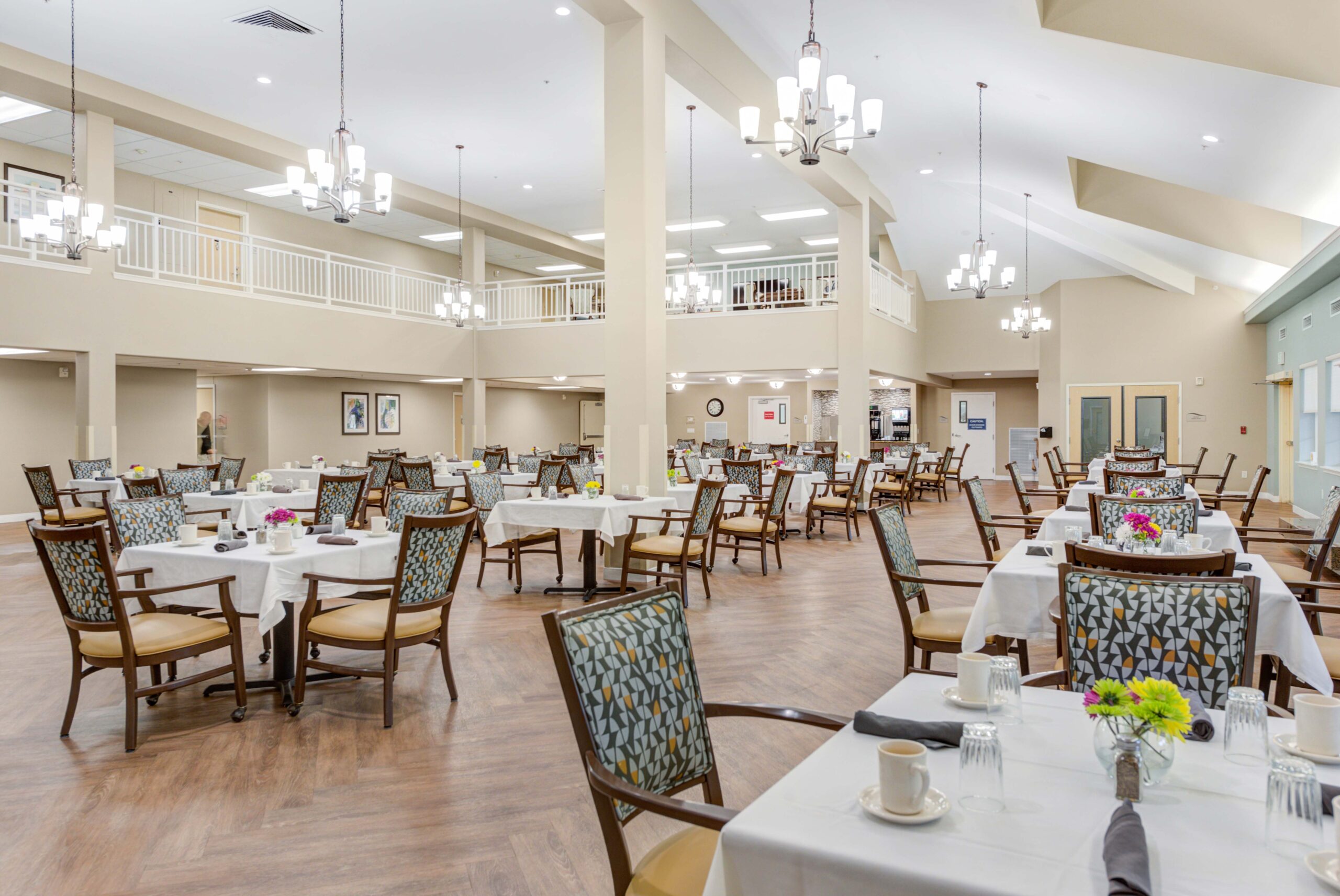 8440-South-Military-Trail-Boynton-Beach-FL-33436-USA_20220810_006-Copy - Windward Palms Interior image of Windward Palms' dining room. The room offers decorated tables, comfortable chairs, and luxurious chandeliers hanging from the ceiling at Windward Palms, a top choice for senior living in Delray Beach.
