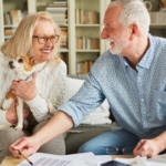 April 25 Events Page Image - Windward Palms Elderly man and woman smiling and holding small dog